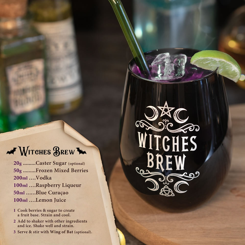 Black stemless wine glass with 'Witches Brew' text, filled with a purple drink, on a wooden surface with bottles in the background.