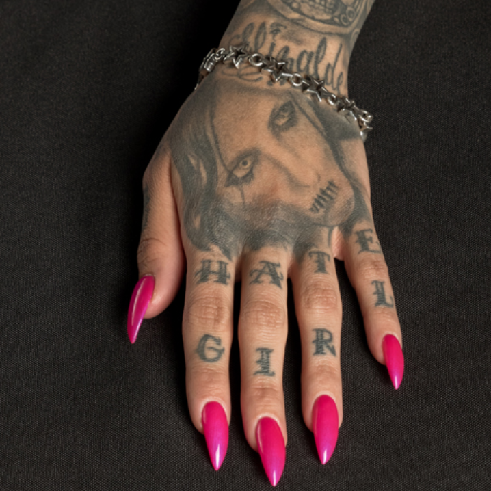 Hand with tattoos and pink nails on a black background