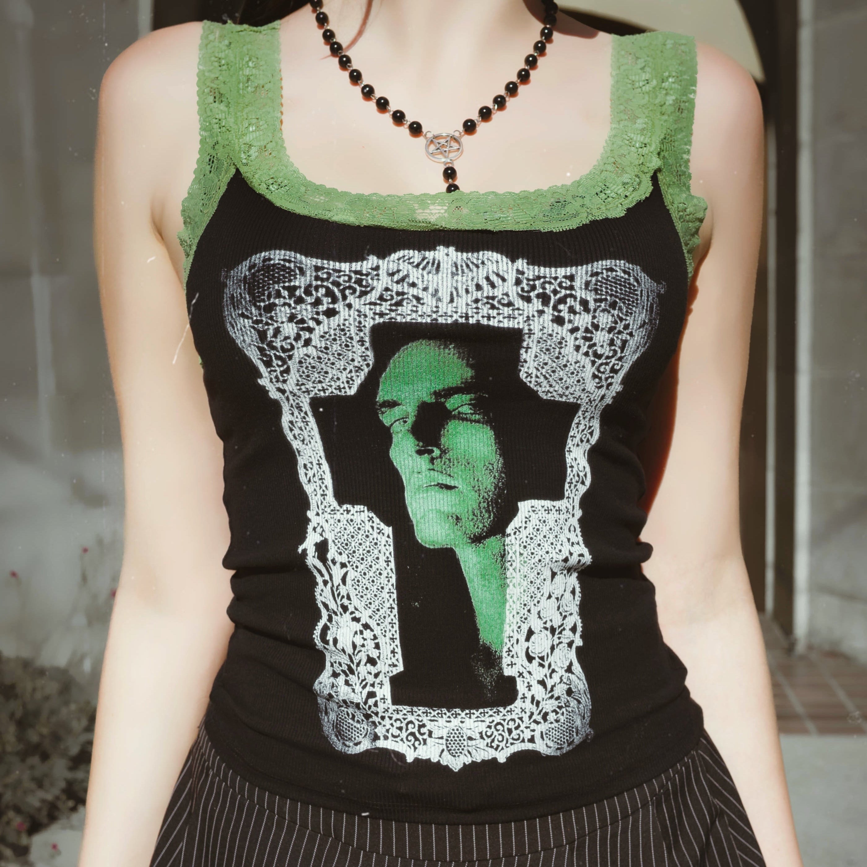 Person wearing a black tank top with a graphic design and a pleated skirt.