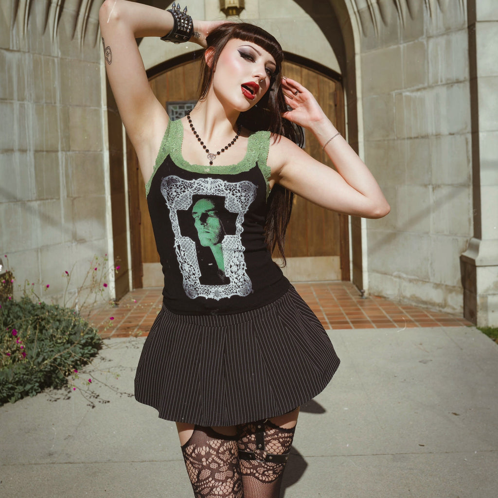 Person wearing a black dress with a graphic design, standing in front of a stone archway.