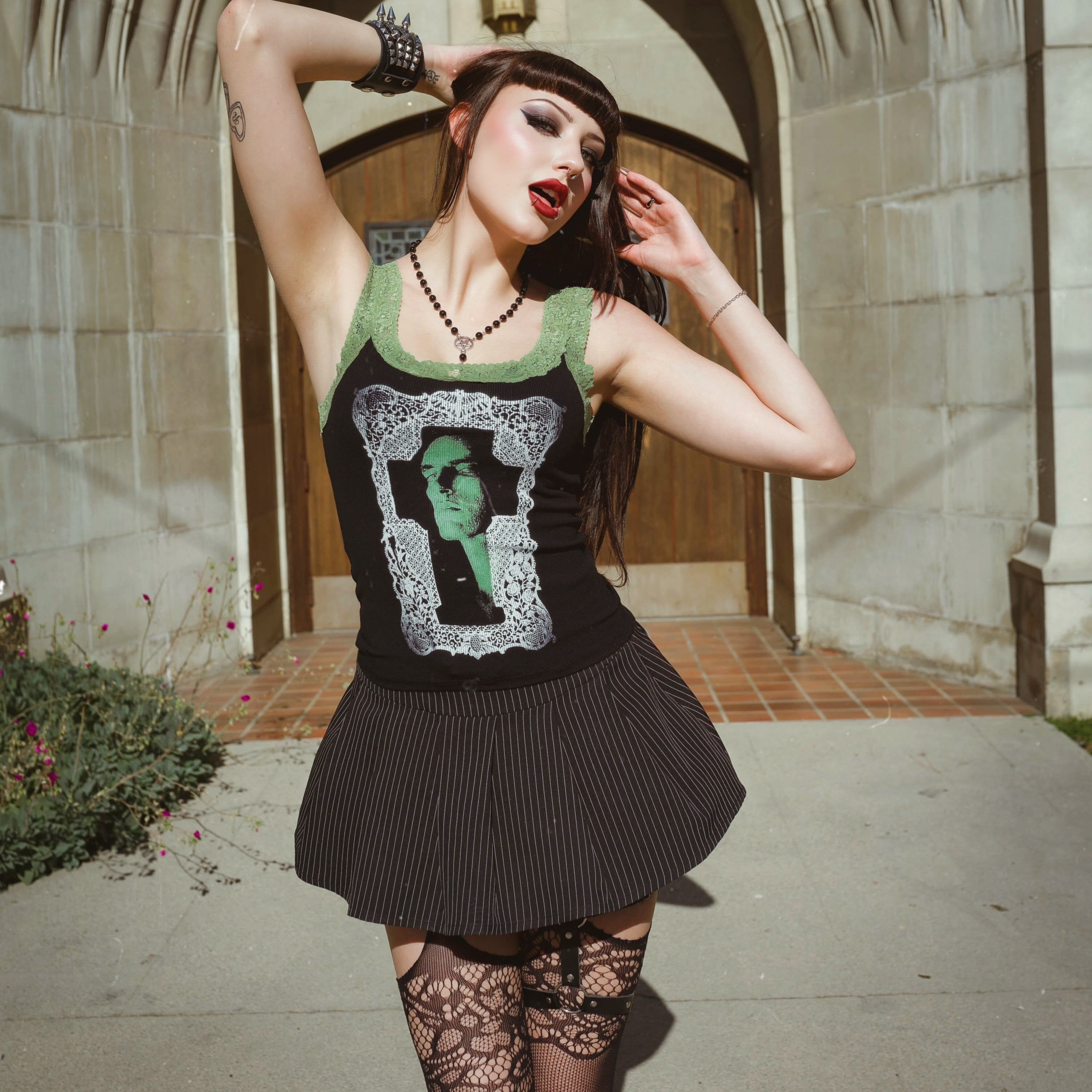 Person wearing a black dress with a graphic design, standing in front of a stone archway.